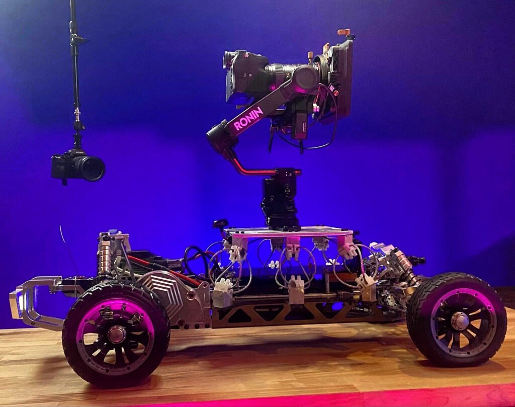Complete 1/5-scale aluminum Baja chassis beneath a camera rig during its gas-to-brushless conversion.